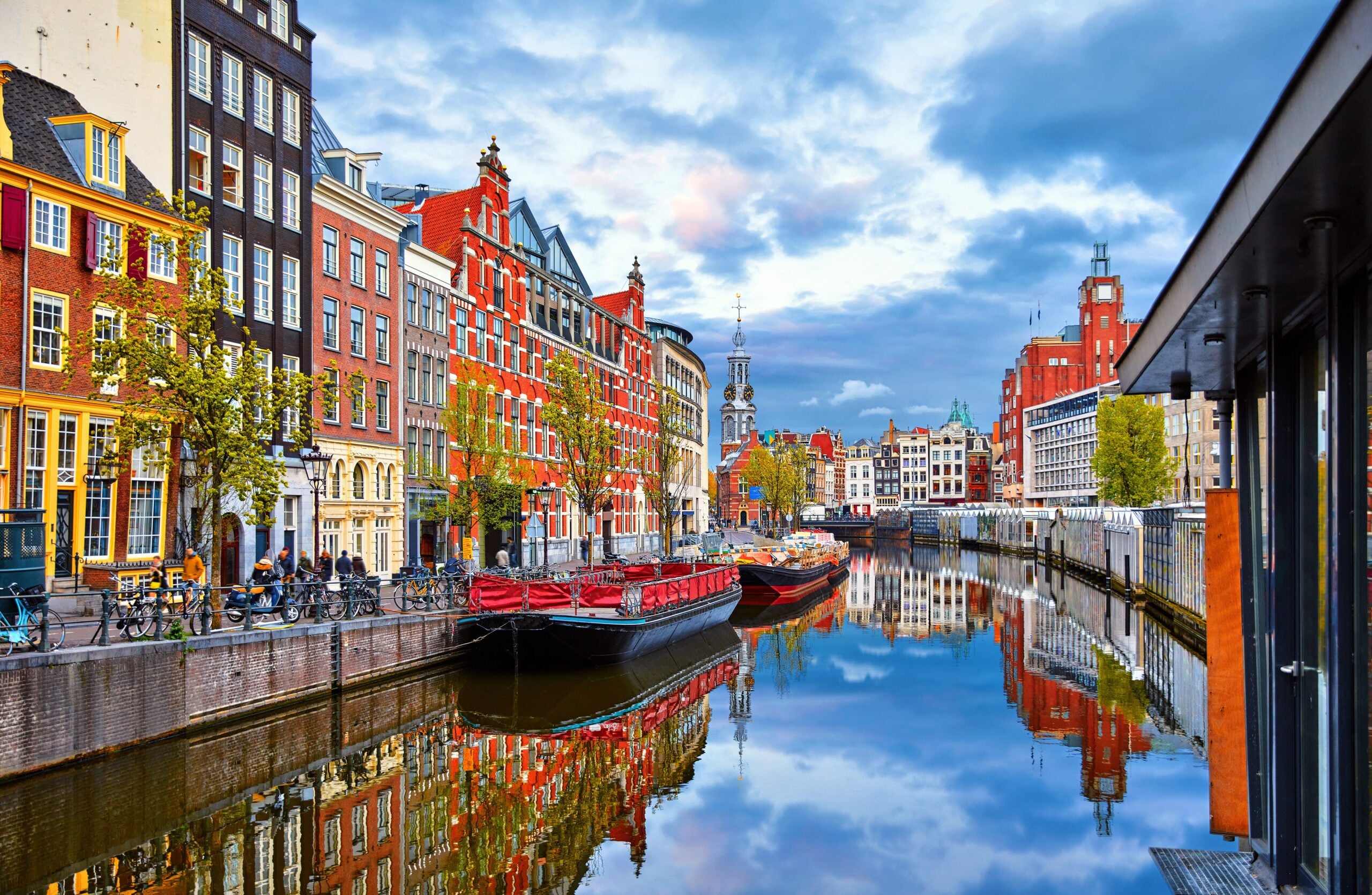 A channel in Amsterdam with colorful boats and homes.